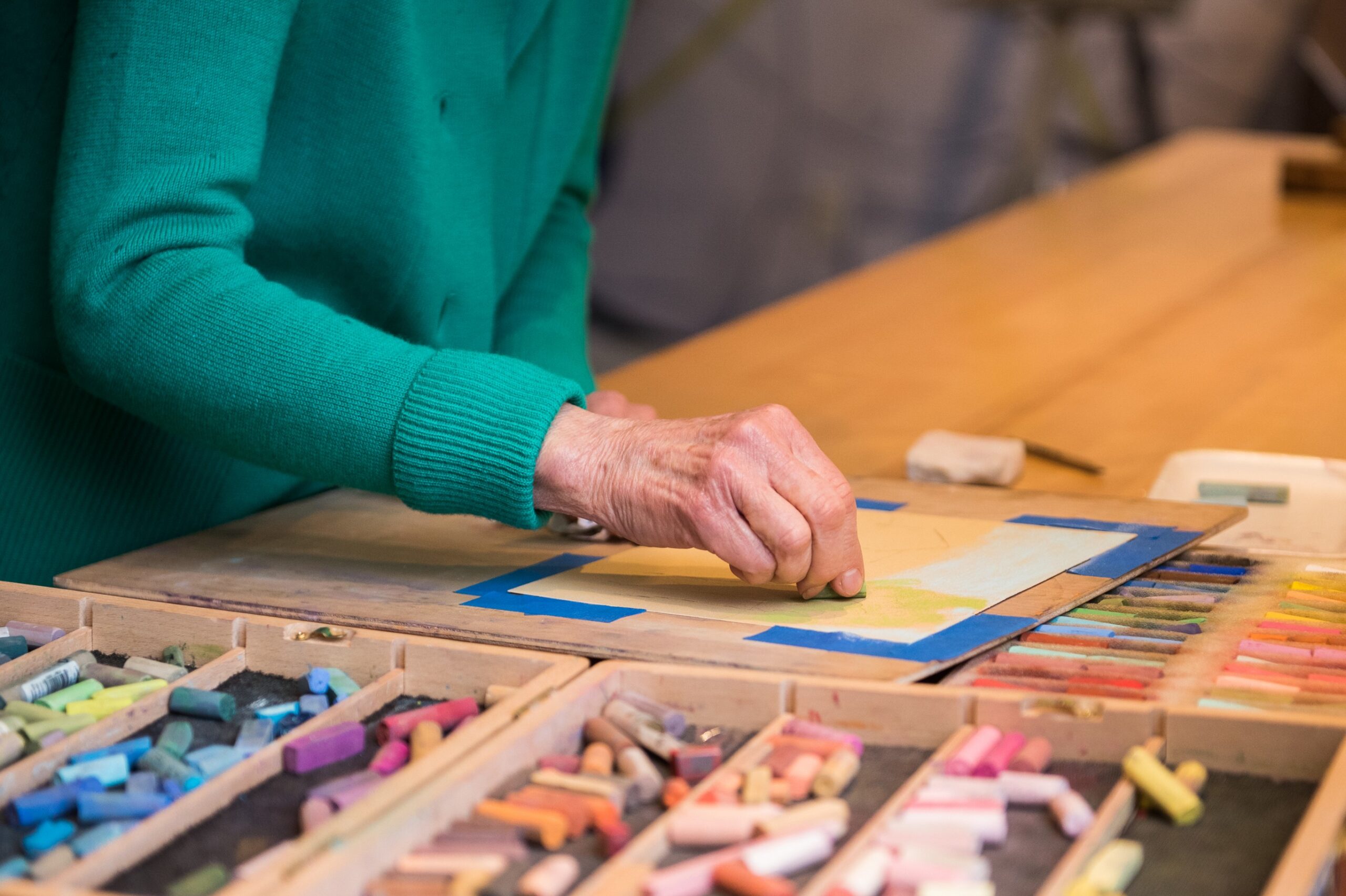 A woman in an independent living retirement community is working on a painting with colored crayons.