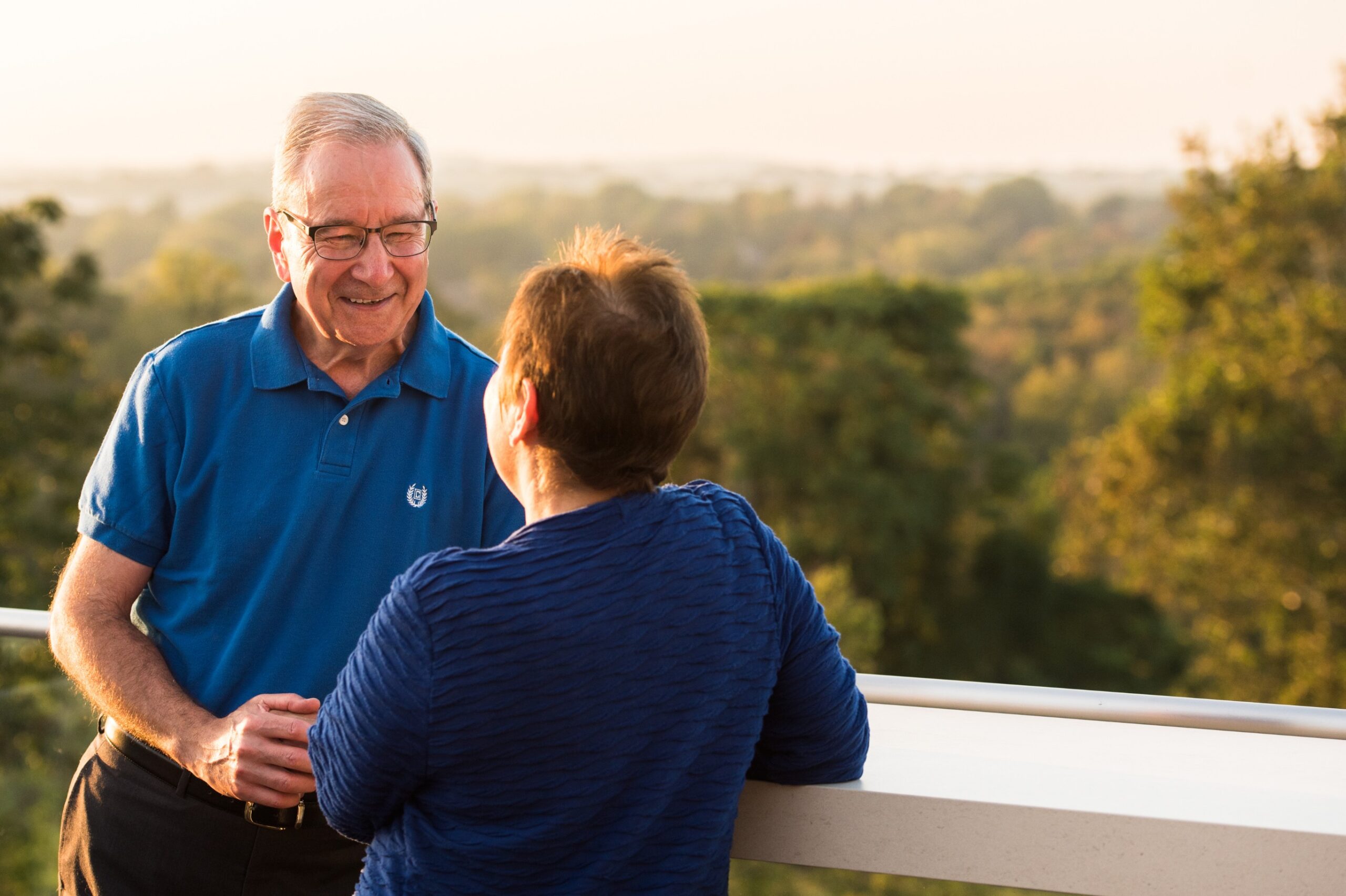 An older couple engaged in independent living talk on a balcony.