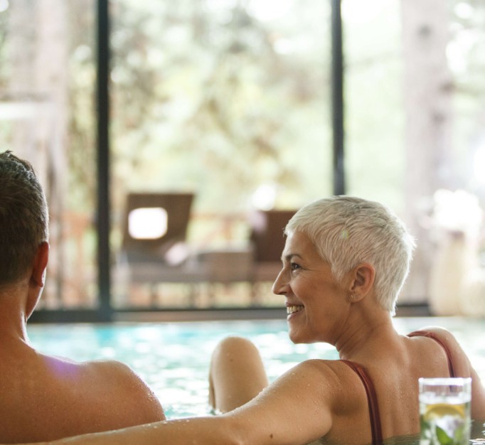 A couple in their 55+ enjoying a hot tub at an independent living retirement community.