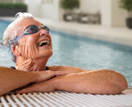 An independent older woman enjoying a swim in the pool wearing goggles.