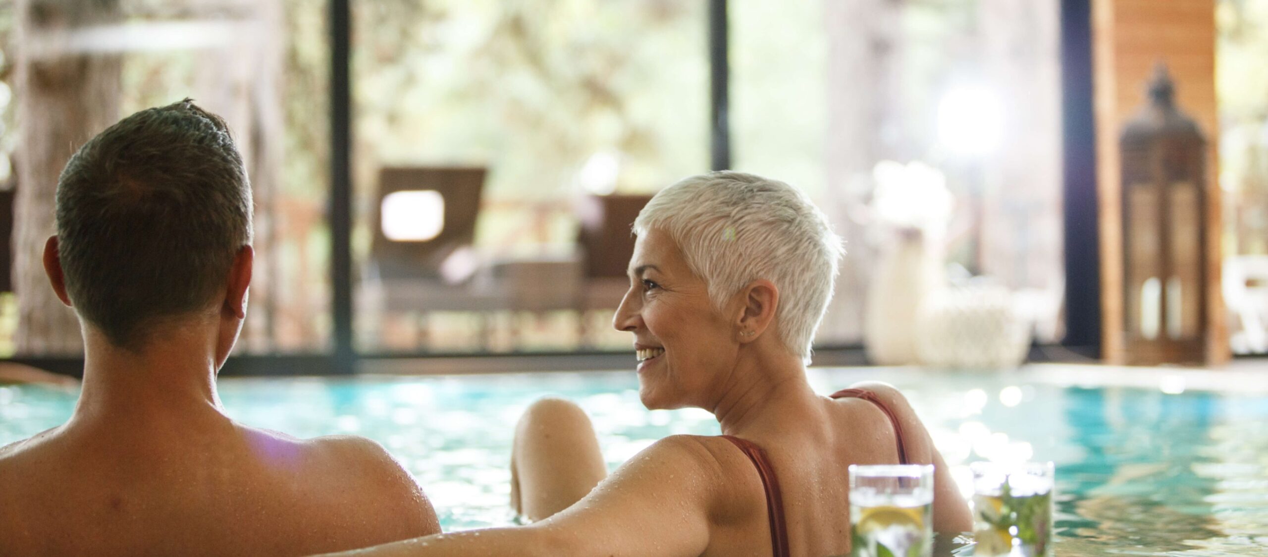 A couple in their 55+ years enjoying independent living by relaxing in a swimming pool at a retirement community.