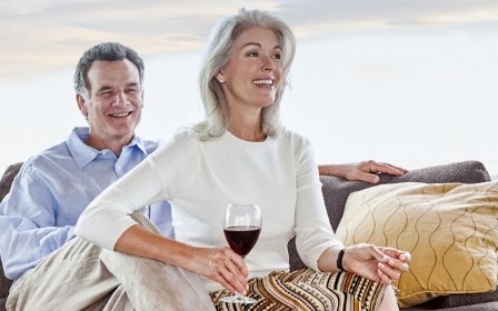 A couple enjoying a glass of wine in their senior living apartment.